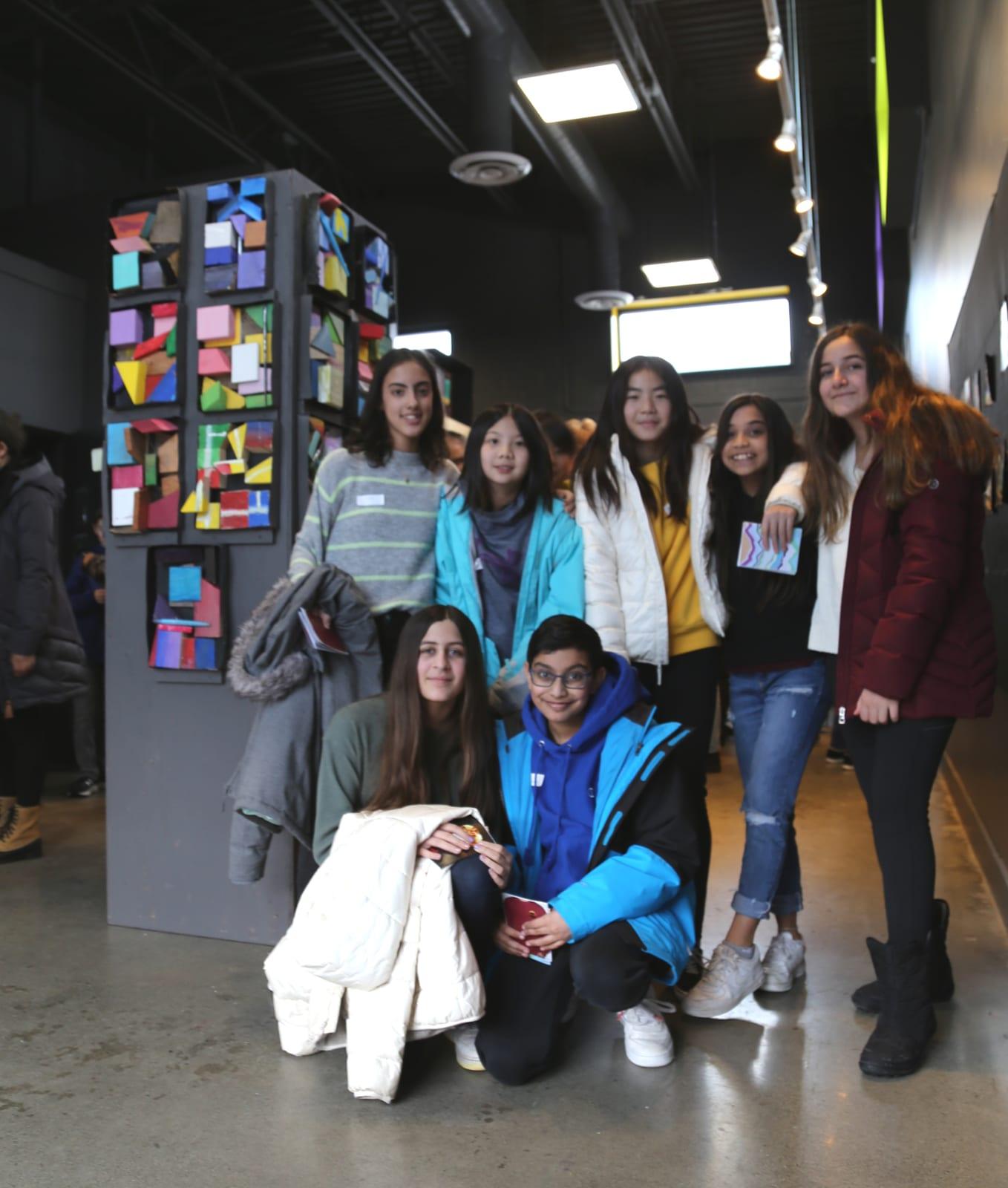 Students beside their collaborative artwork from the Reach to Teach program